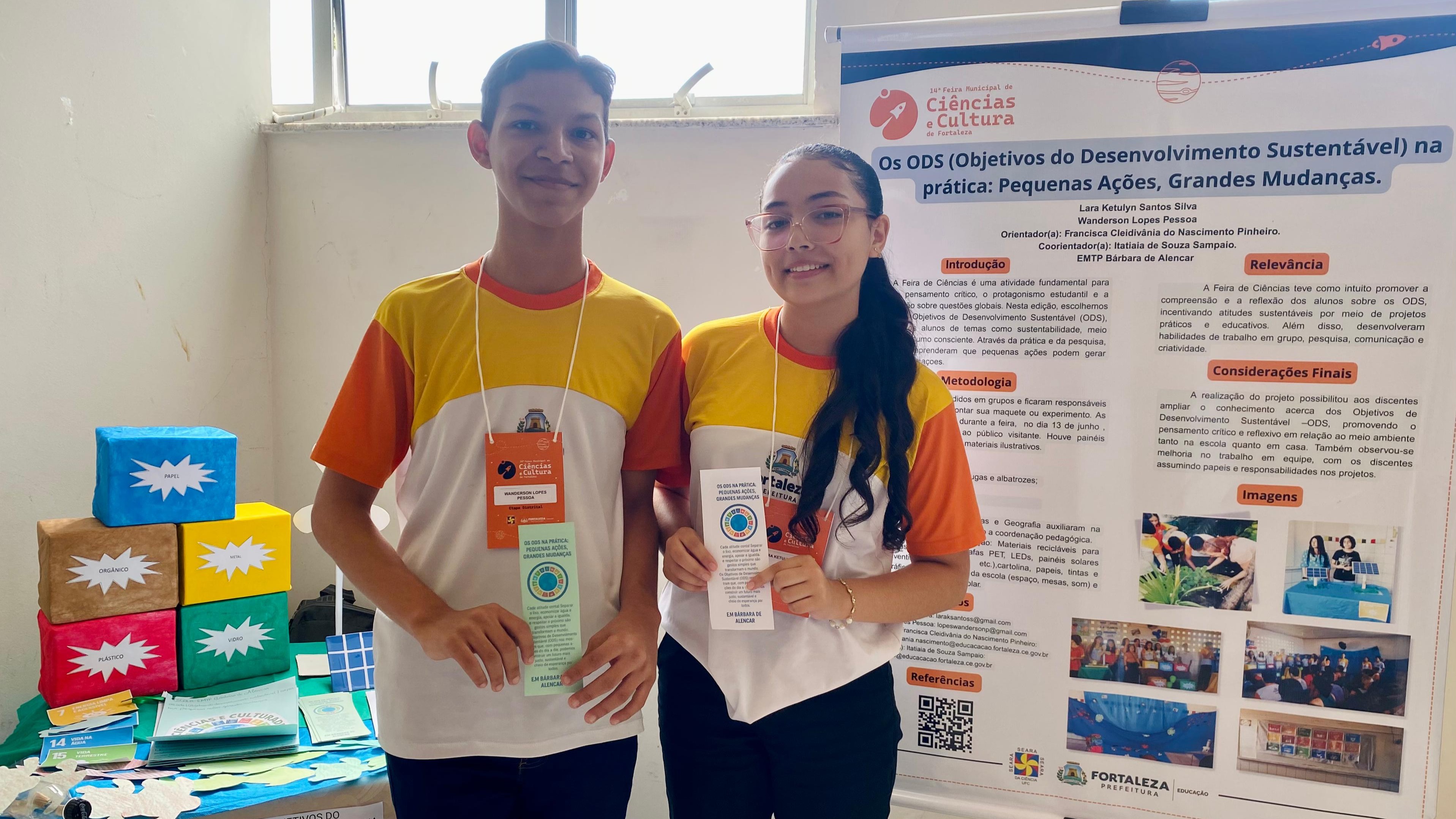 alunos posam ao lado do cartaz de seu projeto de ODS